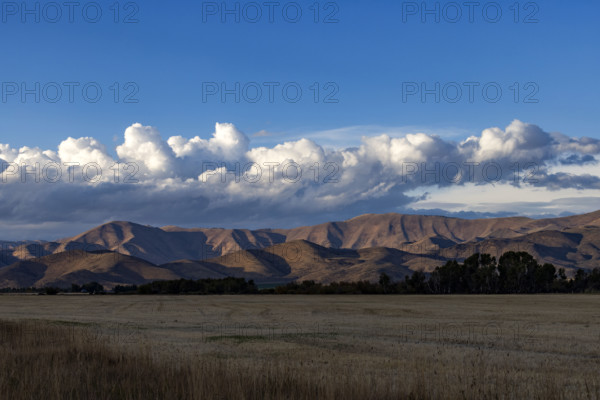 White puffy clouds over mountains and field. Bellevue, Idaho, USA.