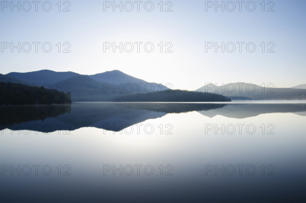 Whiteface Mountain reflected on surface of Lake Placid at sunrise. Lake Placid, New York State, USA.