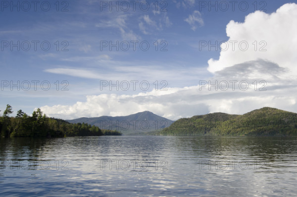 Puffy clouds over calm lake Placid . Lake Placid, New York State, USA.