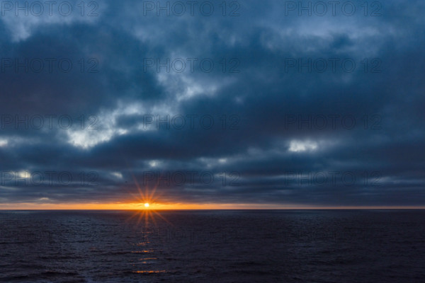 Dark clouds and sun stetting above ocean. La Jolla, California, USA.
