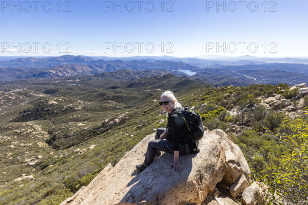 Senior blond hiker looking at view from top of Iron Mountain. Temecula, California, USA.