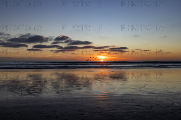 Sun setting over calm ocean. Oceanside, California, USA.