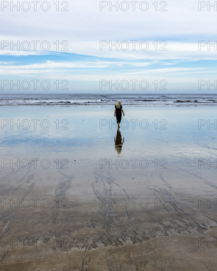 Rear view of senior woman walking on beach at dawn. , Guanacaste, Costa Rica.