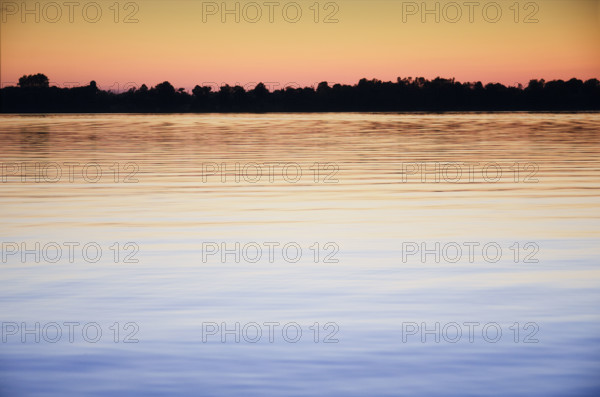 Calm Black Lake reflecting sky at sunset. Hammond, New York State, USA.
