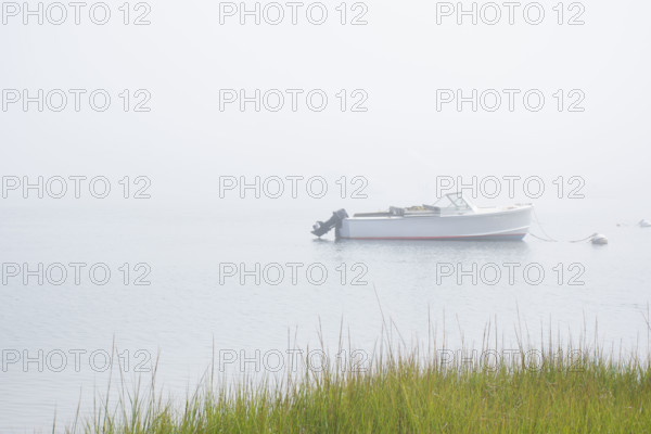 Motorboat anchored on Madaket Harbor on misty morning. Nantucket, Massachusetts, USA.