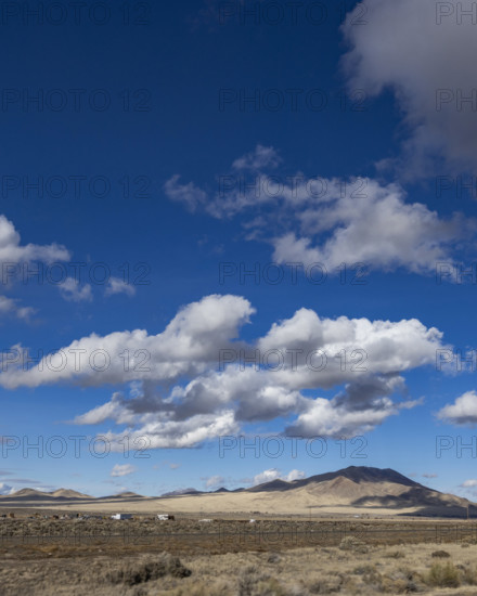 White puffy clouds above Interstate 80 crossing barren landscape, Winnemucca, Nevada, USA.