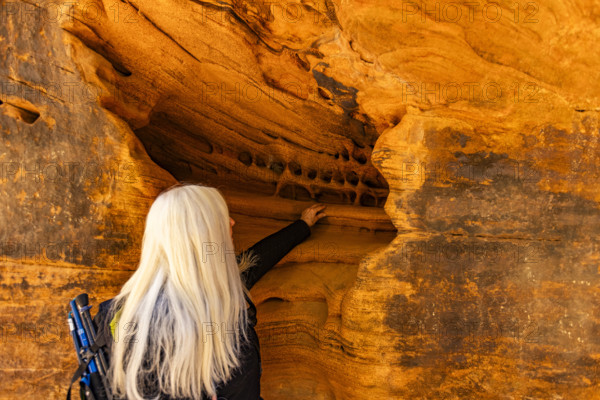 Senior blonde woman touching sandstone formations, Zion National Park, Utah, USA.
