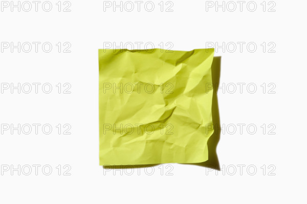 Crumpled yellow post it note on white background, New York City, New York, USA.