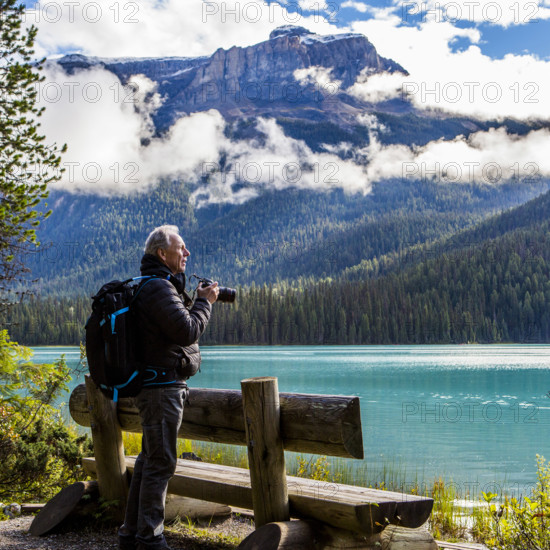 Man photographing mountain lake, Lake Louise, Alberta, Canada.