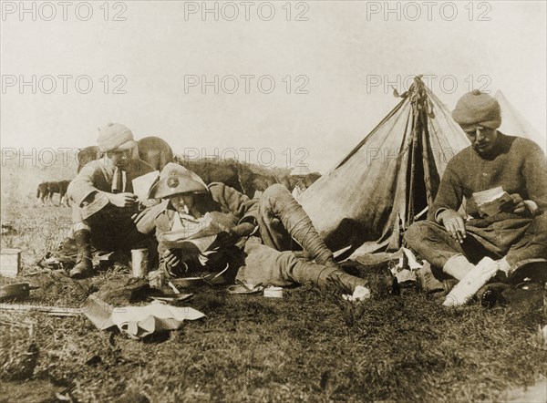 Reading letters from home. An Imperial Yeomanry serviceman, William Ernest Tweedie (right), sits outside his tent at a military camp, reading letters from home with fellow soldiers during the Second Boer War (1899-1902). Krugersdorp, Transvaal (Gauteng), South Africa, November 1900., Gauteng, South Africa, Southern Africa, Africa.