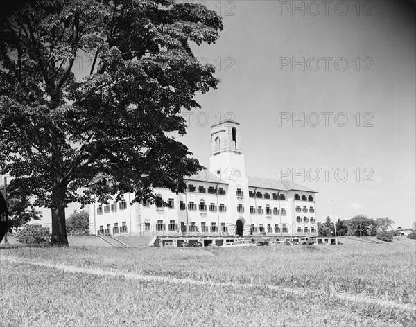 Clock tower at Makerere Hill. A large building with numerous windows and a prominent clock tower is surrounded by open grounds in the district of Makerere Hill. Kampala, Uganda, 12 October 1954. Kampala, Central (Uganda), Uganda, Eastern Africa, Africa.
