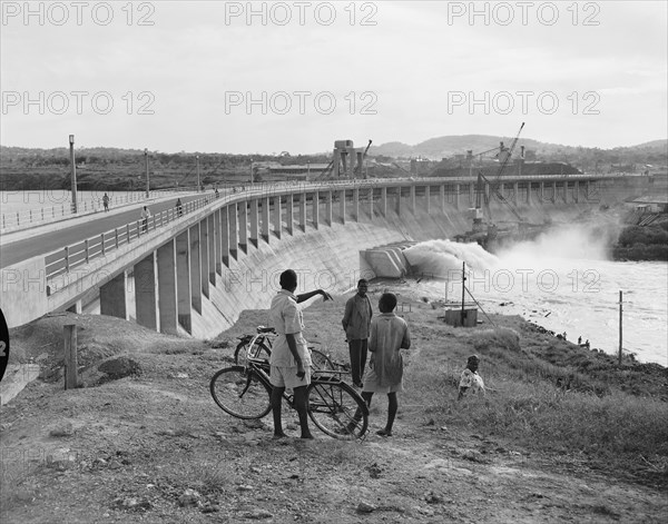 At the newly completed Owen Falls Dam. People with bicycles chat at the site of the brand new Owen Falls Dam (Nalubaale Dam) across the White Nile River, the construction of which was completed in 1954. Near Jinja, Eastern Region, Uganda, 12 October 1954., East (Uganda), Uganda, Eastern Africa, Africa.