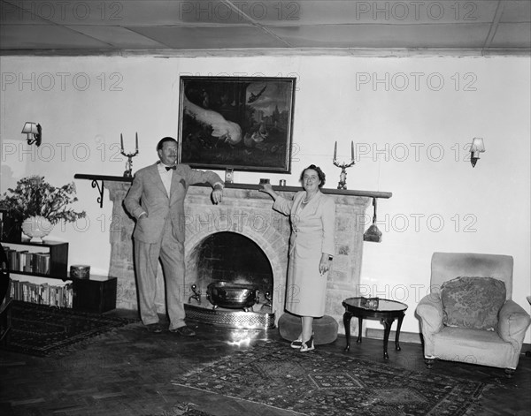 Roddy and Noreen. Roddy and his wife Noreen pose for a photograph leaning against a large fireplace in a colonial house. Taken on the christening of Peter Buchanan's baby. Nairobi, Kenya, 23 October 1954. Nairobi, Nairobi Area, Kenya, Eastern Africa, Africa.