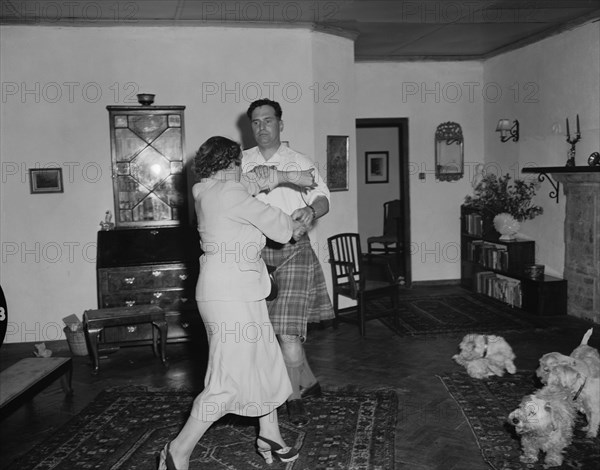 Highland jig. Peter Buchanan and Noreen dancing in a colonial house on the christening of Peter's baby. Four West Highland terriers can be seen on the right of the photograph. Nairobi, Kenya, 23 October 1954. Nairobi, Nairobi Area, Kenya, Eastern Africa, Africa.