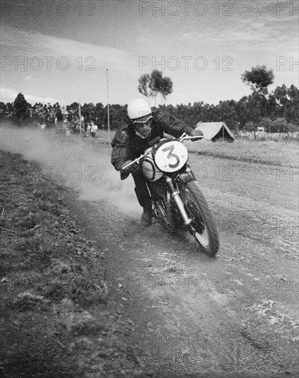 Race seven. Motorcycle rider Vic Preston puts his foot down during race seven at the Eldoret race meeting. Eldoret, Kenya, 27 December 1954. Eldoret, Rift Valley, Kenya, Eastern Africa, Africa.