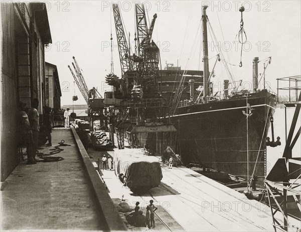 Loading grain on SS Modasa. SS Modasa docked at Kilindini harbour. Mombasa, Kenya, circa 1930. Mombasa, Coast, Kenya, Eastern Africa, Africa.