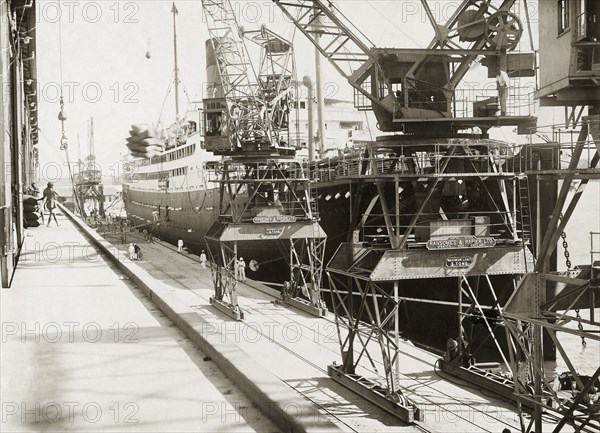 Dockside view at Kilindini harbour. SS Franconia and cranes on the dockside at Kilindini harbour. Mombasa, Kenya, circa 1930. Mombasa, Coast, Kenya, Eastern Africa, Africa.