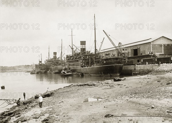 Steamers berthed at Kilindini harbour. Three near-sister cargo vessels from the British India Steam Navigation Company's fleet docked at Kilindini harbour. The ships have twin masts with a single funnel, painted in BISN's colours of black with two white bands. Mombasa, Kenya, circa 1930. Mombasa, Coast, Kenya, Eastern Africa, Africa.