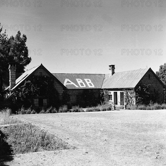 Gabb's house. A single storey house with tall chimneys displays the large painted letters 'GABB', the name of the owner of the house. During the Mau Mau campaigns of the 1950s, house owners used signs such as this to announce which side they were affiliated to. North Kinangop, Kenya, 9-12 February 1953. Kinangop, Central (Kenya), Kenya, Eastern Africa, Africa.