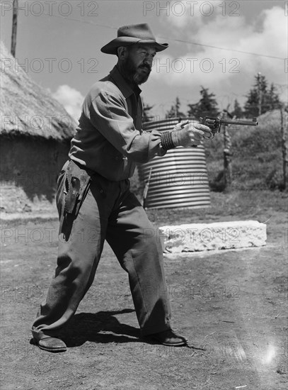 Davo' Davidson takes aim. Davo' Davidson aims a revolver. Kenya, 22 May 1953. Kenya, Eastern Africa, Africa.