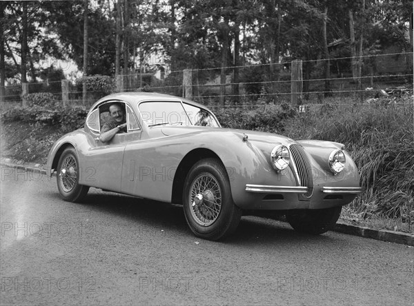 Peter Knight's Coupe Jaguar. Peter Knight smiles for the camera from the window of his Coupe Jaguar car. Kenya, 7 June 1953. Kenya, Eastern Africa, Africa.