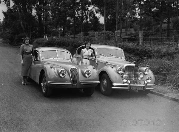 Wives and Jaguars. Two women with their husbands' cars: Peter Knight's Jaguar Coupe (left) and Archer's Jaguar Mark V (right). Kenya, 7 June 1953. Kenya, Eastern Africa, Africa.