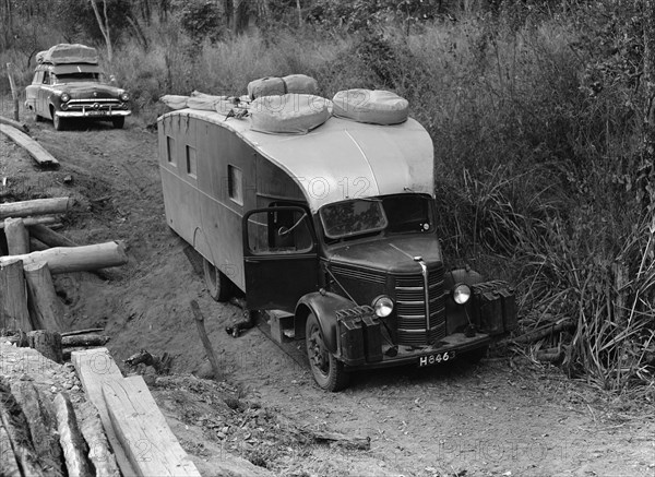 Stuck in the mud. An old-fashioned caravan is stuck on an uneven dirt path. The vehicle's registration number matches that on related photographs and belongs to the Price family. Nyasaland (Malawi), September 1953. Malawi, Southern Africa, Africa.