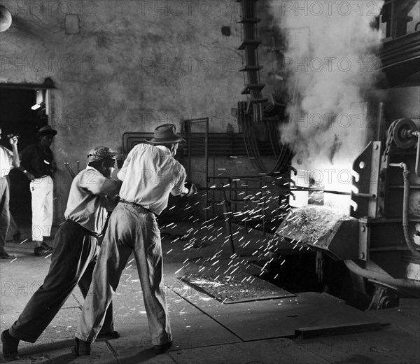 Sparks fly at a railway workshop. A publicity photograph from the East African Railways and Harbours Administration (EAR&H) showing factory workers forging metal in the railways workshops. Nairobi, Kenya, circa 1960. Nairobi, Nairobi Area, Kenya, Eastern Africa, Africa.