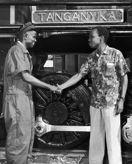 Julius Nyerere greets a train driver. A publicity photograph from the East African Railways and Harbours Administration (EAR&H) shows Dr Julius Nyerere, the first leader of independent Tanganyika, shaking hands with a train driver in front of a train bearing the name plate 'Tanganyika'. Tanganyika (Tanzania), circa 1961. Tanzania, Eastern Africa, Africa.
