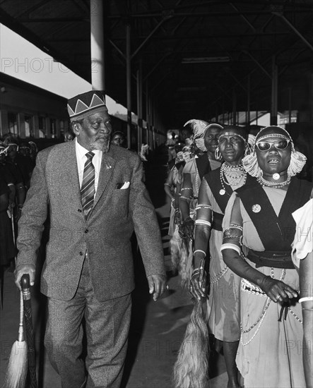 Jomo Kenyatta with his female bodyguard. Jomo Kenyatta, new leader of independent Kenya, walks along a railway platform accompanied by members of his female bodyguard. Kenya, circa 1963. Kenya, Eastern Africa, Africa.
