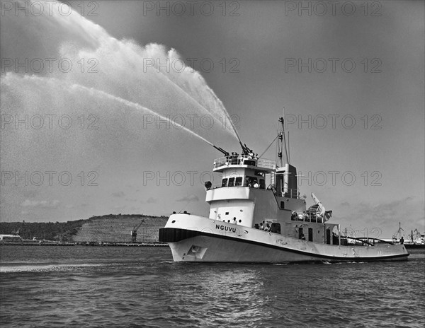 Port tug Nguvu firing water cannon. A publicity photograph from the Port Division of the East African Railways and Harbours Administration (EAR&H) showing the port tug Nguvu (from the Swahili for 'strong') firing its water cannon. Tanganyika Territory (Tanzania), circa 1955. Tanzania, Eastern Africa, Africa.