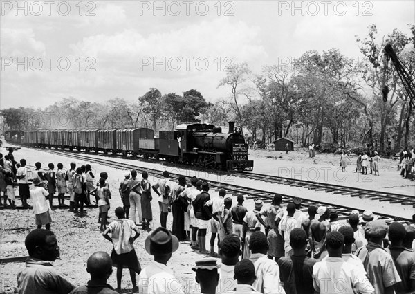 People greet the first train to Nachingwea. A publicity photograph from the East African Railways and Harbours Administration (EAR&H) shows a crowd of Tanganyikan people watching the first train from Mkwaya to Nachingwea. Tanganyika Territory (Tanzania), 25 October 1949. Tanzania, Eastern Africa, Africa.