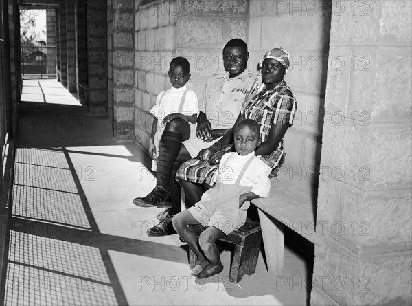 Railway family in Kenya. A publicity photograph from the East African Railways and Harbours Administration (EAR&H) showing a railway worker and his wife and two sons on the veranda of their new block of company flats. Nairobi, Kenya, circa 1960. Nairobi, Nairobi Area, Kenya, Eastern Africa, Africa.