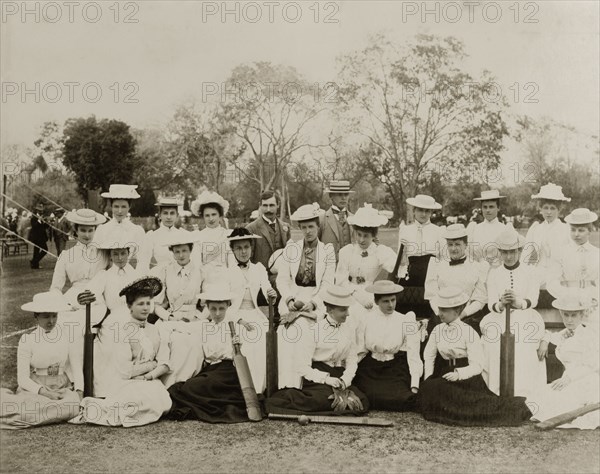 Victorian ladies' cricket. Two ladies' cricket teams in their sporting whites pose for the camera before a match. All of the women wear Victorian-style clothing including boater hats and long skirts belted tightly at the waist. Several of the group hold cricket bats. India, 1893. India, Southern Asia, Asia.