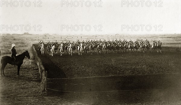 Practice cavalry charge. British men from an Indian Army cavalry unit perform a practice charge across a fenced arena with their standards raised. India, circa 1880. India, Southern Asia, Asia.