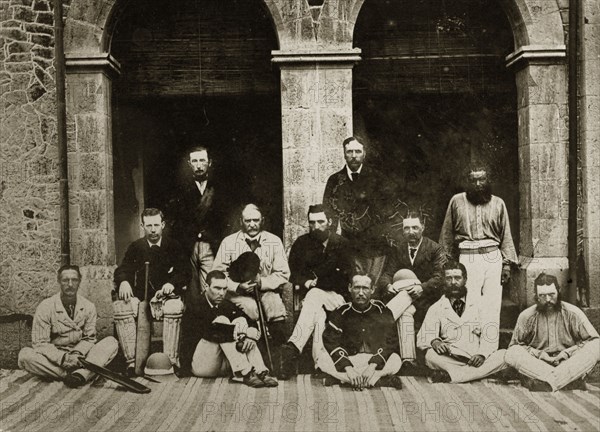 Satara and Poona cricket teams. Group portrait of the Satara and Poona cricket teams dressed in their whites outside a building with arched doorways. Bombay (Mumbai), India, circa 1875. Mumbai, Maharashtra, India, Southern Asia, Asia.