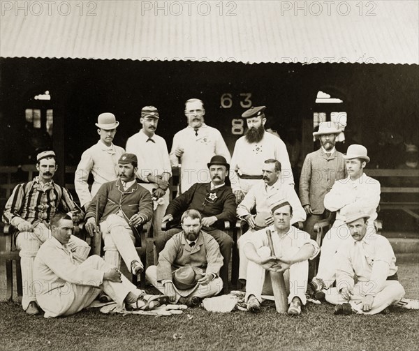 Members of the north Bombay cricket team. Group portrait of members of the north Bombay cricket team dressed in their sporting whites outside a clubhouse. Two of the men wear padded leg guards, another holds a cricket bat. Bombay (Mumbai), India, circa 1875. Mumbai, Maharashtra, India, Southern Asia, Asia.
