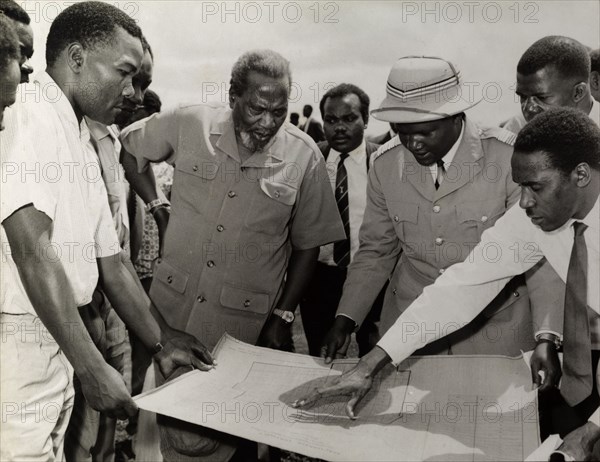 Jomo Kenyatta meets town planners. Farm planners gather around a blueprint to explain their proposals to Jomo Kenyatta, the first president of an independent Kenya. Fort Hall, Kenya, circa 1965. Fort Hall, Central (Kenya), Kenya, Eastern Africa, Africa.