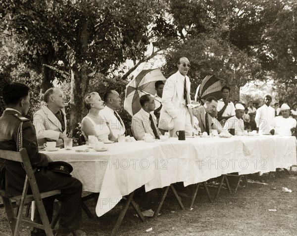 Speech at Rangoon Golf Club. R.B. Groves, a Captain of the Rangoon Golf Club, stands to deliver a speech surrounded by club council members. Rangoon (Yangon), Burma (Myanmar), circa 1952. Yangon, Yangon, Burma (Myanmar), South East Asia, Asia.