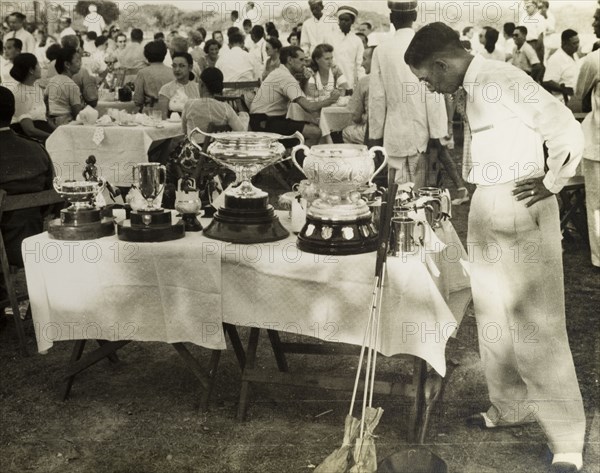 Golf trophies, Burma (Myanmar). An interested member of the press surveys a selection of golf trophies at an awards ceremony for the Burma Open Championship being held at the Rangoon Golf Club. Rangoon (Yangon), Burma (Myanmar), circa 1952. Yangon, Yangon, Burma (Myanmar), South East Asia, Asia.