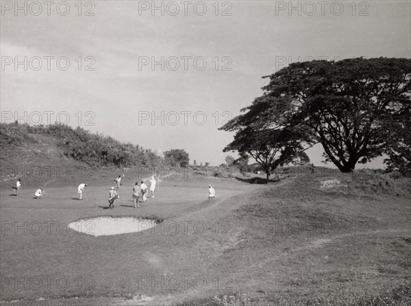 Playing golf, Rangoon. Golfers play a round on an uneven section of the golf course at Rangoon Golf Club. Rangoon (Yangon), Burma (Myanmar), circa 1952. Yangon, Yangon, Burma (Myanmar), South East Asia, Asia.