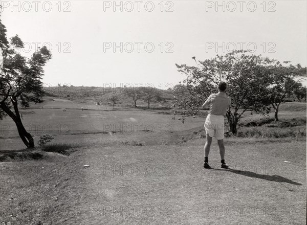 Playing golf, Rangoon. A lone golfer follows his shot, club still swung high in the air, on the course at Rangoon Golf Club. Rangoon (Yangon), Burma (Myanmar), circa 1952. Yangon, Yangon, Burma (Myanmar), South East Asia, Asia.