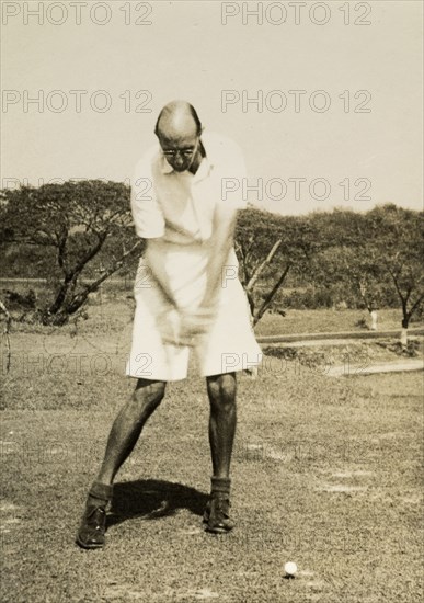 Stiff left side'. R.B. Groves, a Captain of the Rangoon Golf Club, takes a swing at the ball on the club's golf course. Groves comments about the shot: 'The result was a good one straight down the middle. My knees were too far apart to hear them knocking'. Rangoon (Yangon), Burma (Myanmar), circa 1952. Yangon, Yangon, Burma (Myanmar), South East Asia, Asia.