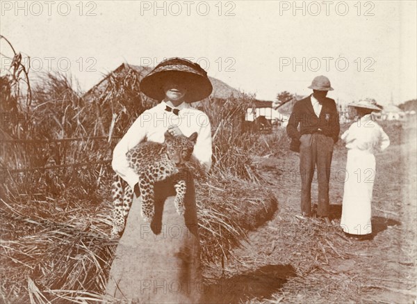 A formidable beast. A European woman wearing a large sun hat holds an Indian Leopard cub (Panthera pardus fusca) under her arm. Probably Burma (Myanmar), circa 1905. Burma (Myanmar), South East Asia, Asia.