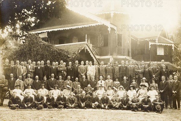 Group portrait outside a colonial house. A large number of formally dressed European men and women pose for a group portrait outside an ornate, colonial house. Probably Burma (Myanmar), 1921. Burma (Myanmar), South East Asia, Asia.
