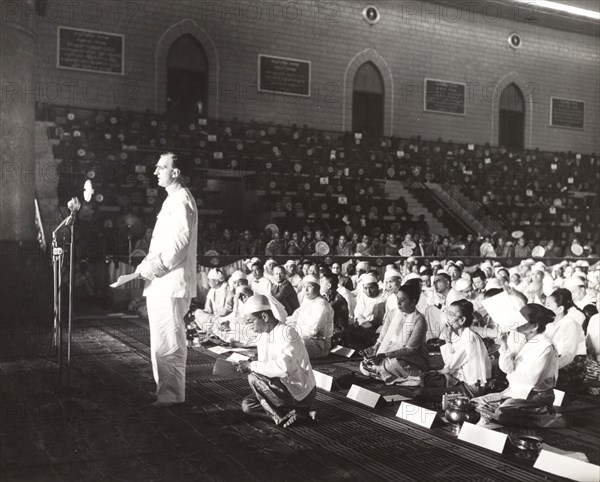 Addressing the sixth Buddhist Synod. A European man stands before a microphone, addressing a Buddhist congregation during the sixth Buddhist Synod. Rangoon (Yangon), Burma (Myanmar), 1954. Yangon, Yangon, Burma (Myanmar), South East Asia, Asia.