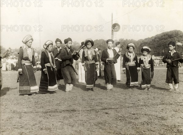 Burmese musicians. A party of Burmese musical performers in traditional dress perform at an outdoor event. The women dance to the accompaniment of wind and string instruments played by the men. Burma (Myanmar), circa 1940. Burma (Myanmar), South East Asia, Asia.