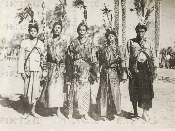 Five Asian men in ceremonial dress. Portrait of five Asian men, dressed in ceremonial attire including embroidered robes and elaborately feathered headdresses. Probably Burma (Myanmar), circa 1905. Burma (Myanmar), South East Asia, Asia.