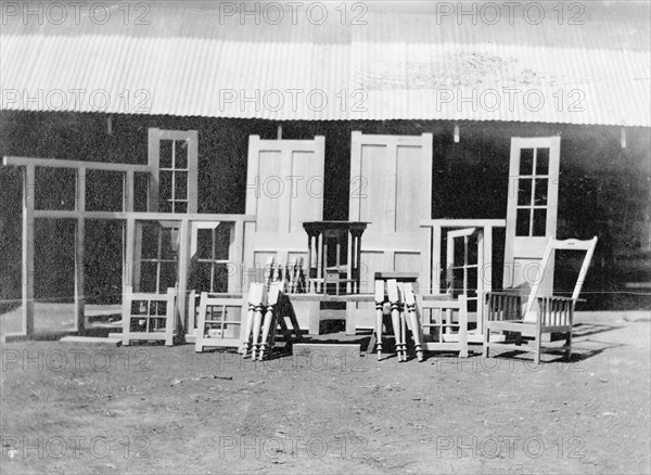 Furniture exhibition. Furniture on exhibition including doors, window frames, chairs, tables and assorted furniture legs. The items were made by employees of the Public Works Department working under the supervision of Charles Bungey, a training officer with the PWD. Nakuru, Kenya, 1922. Nakuru, Rift Valley, Kenya, Eastern Africa, Africa.
