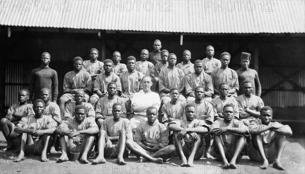 Apprentices in the Public Works Department. Group portrait showing Charles Bungey, a training officer in the Kenyan Public Works Department, seated in the centre of 30 young African men. Nakuru, Kenya, circa 1923. Nakuru, Rift Valley, Kenya, Eastern Africa, Africa.